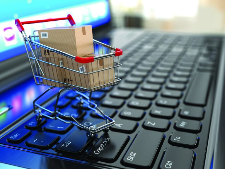 E-commerce. Shopping cart with cardboard boxes on laptop